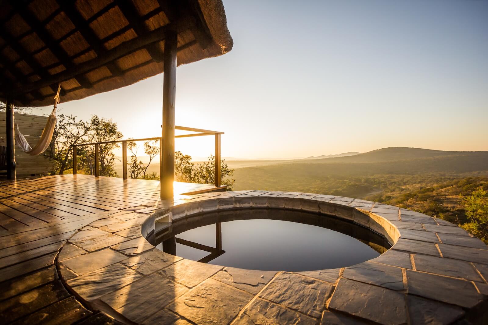 A private plunge pool on a wooden deck at sunset, overlooking the Lebombo Mountains at Leopard Mountain Safari Lodge, a luxury cliffside retreat in South Africa.
