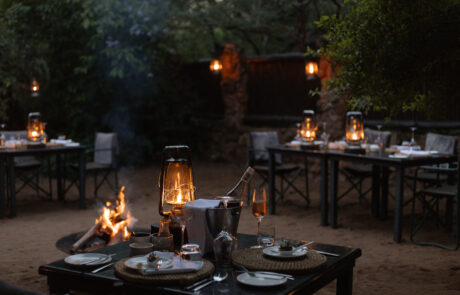 Table set for a private boma dinner with lanterns and an open fire at Leopard Mountain