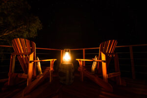 Two chairs facing a starry night sky, with a lantern glowing between them