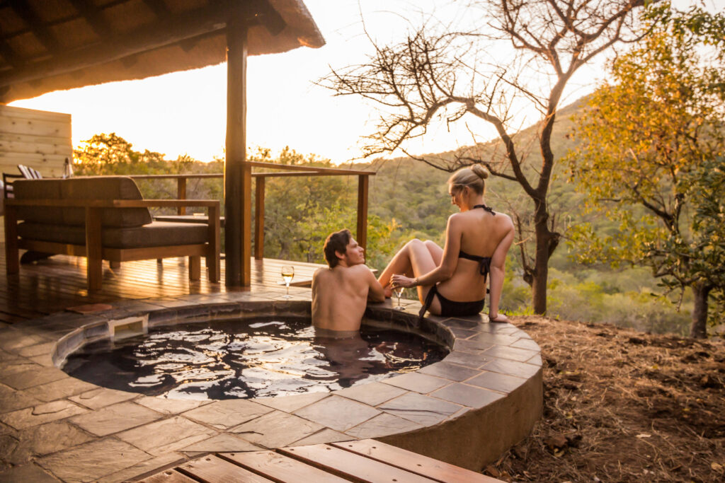 Couple in a private plunge pool at sunset on a romantic getaway at Leopard Mountain